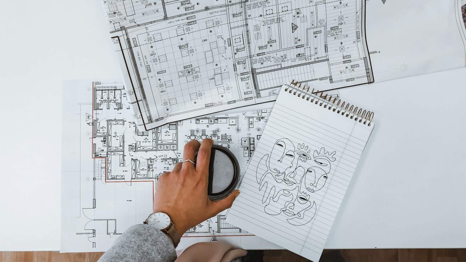 Hands reviewing floor plans for a conversion scheme